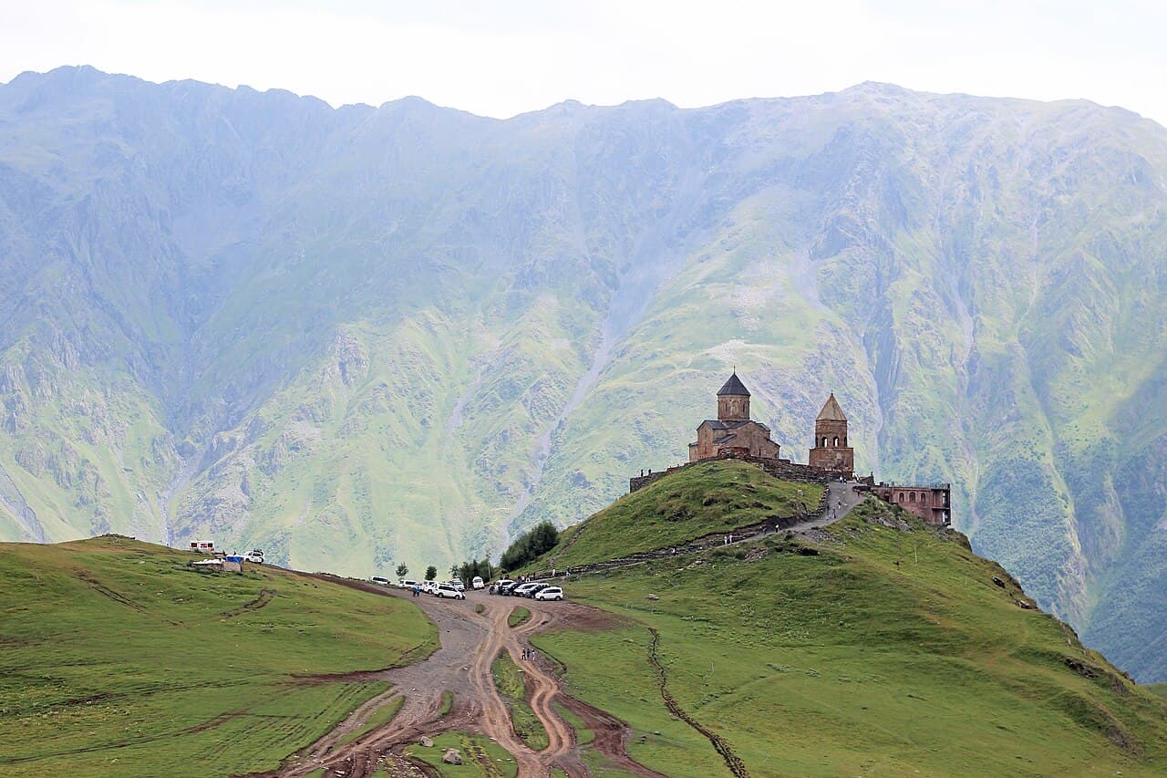 En ensom steinkirke på en høyde med det snødekte Kazbek-fjellet bak