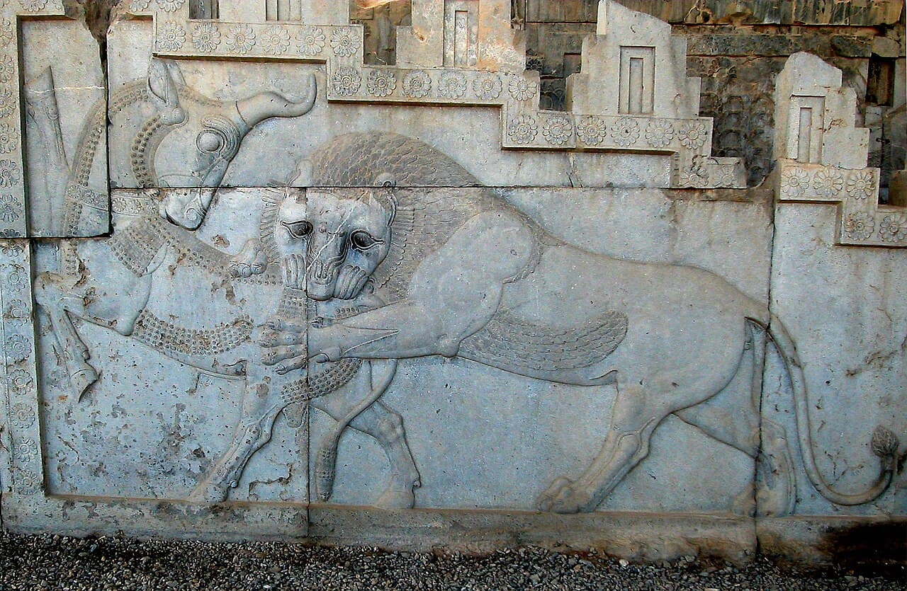 Steinrelieff av en løve som angriper en okse på trappen i Persepolis
