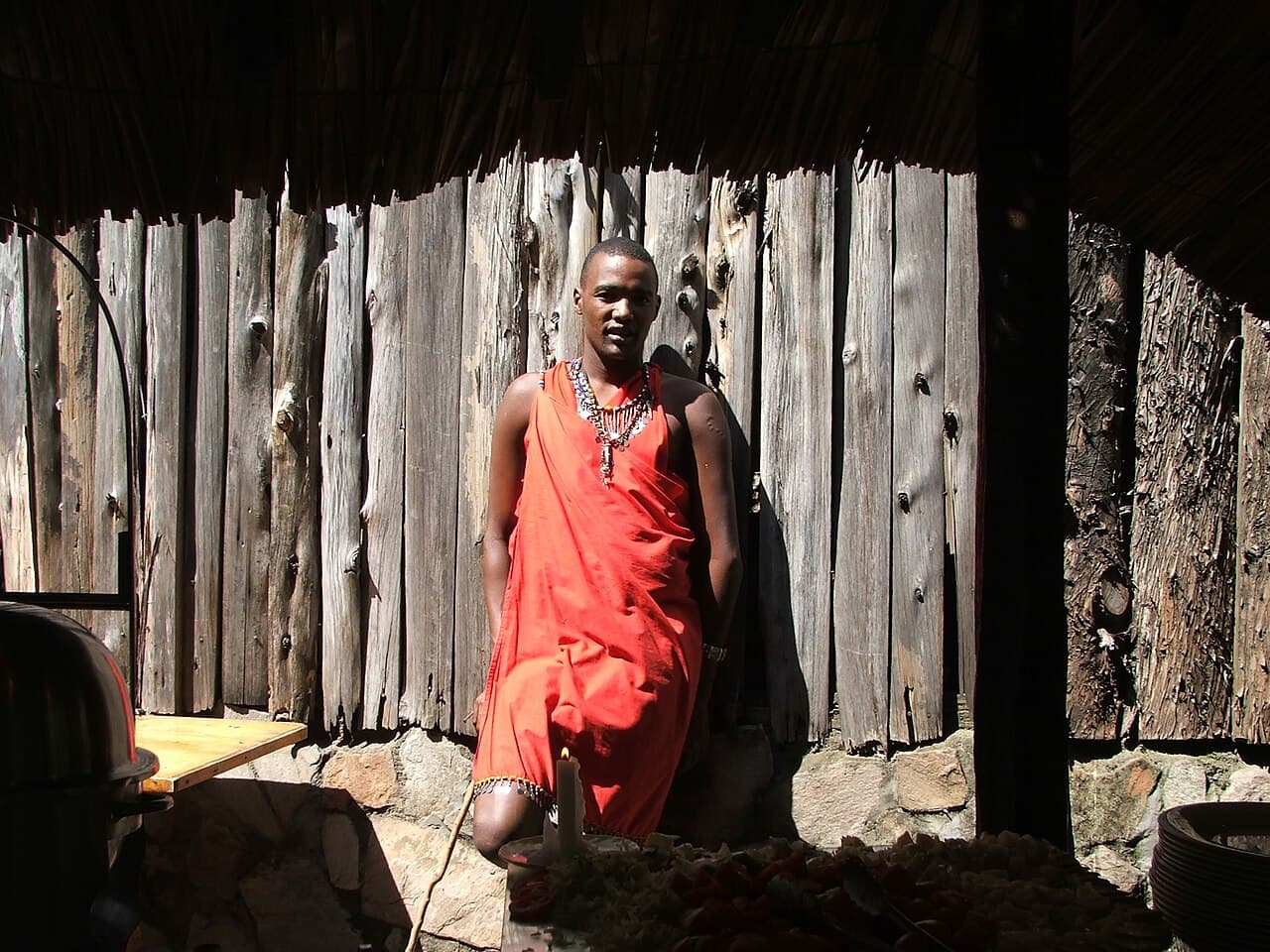 En Maasai-kriger i rød kappe på savannen