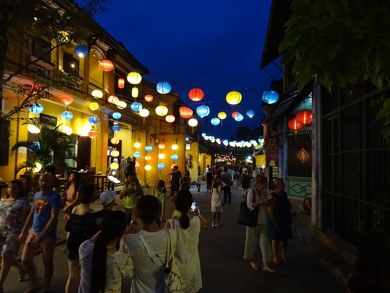 Fargerike papirlykter henger tett over en gate i Hoi An