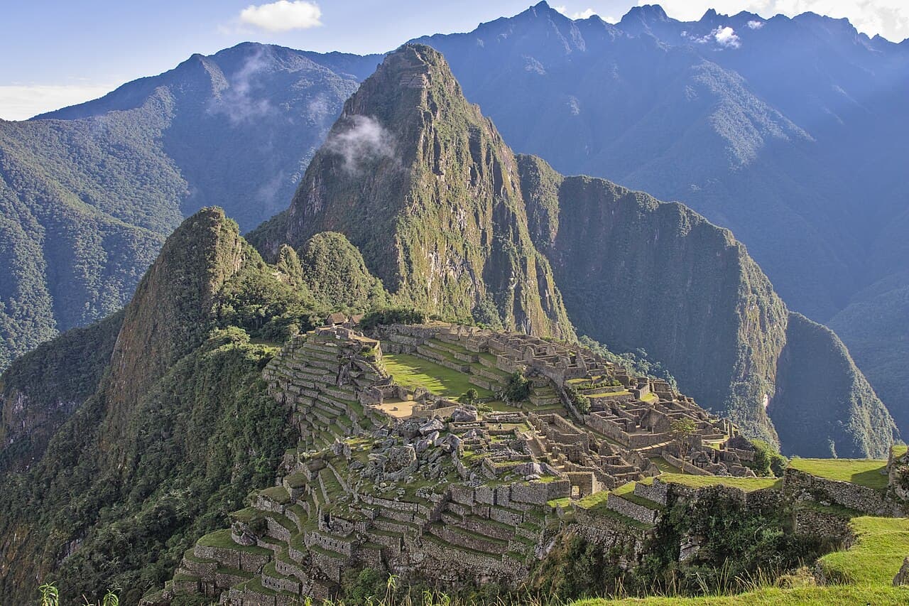 Ruinbyen Machu Picchu med grønne terrasser og fjelltopper bak